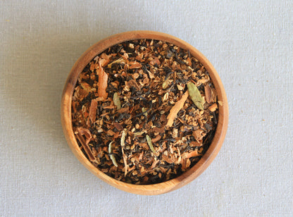 Herbal blend Exotic Feeling in a wooden bowl, allows us to see all the ingredients; assam black tea, cardamom, dried ginger, star anise, black peppercorn, nutmeg, cinnamon, clove