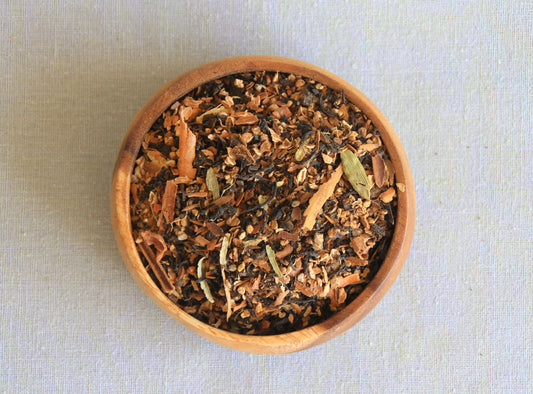 Herbal blend Exotic Feeling in a wooden bowl, allows us to see all the ingredients; assam black tea, cardamom, dried ginger, star anise, black peppercorn, nutmeg, cinnamon, clove