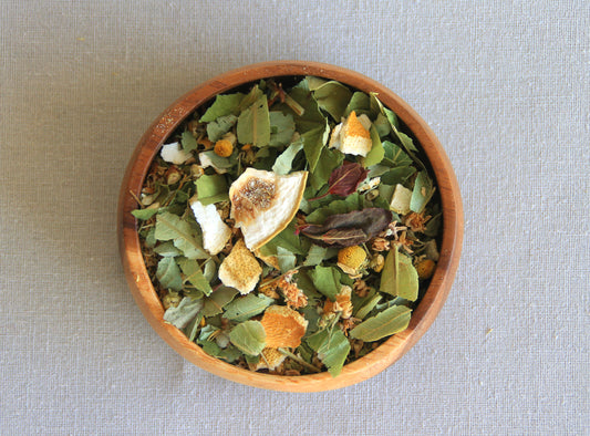 Herbal blend Lullaby in a wooden bowl, allows us to see all the ingredients; hipericão-de-gêres, dried lemon peel, linden, camomilla