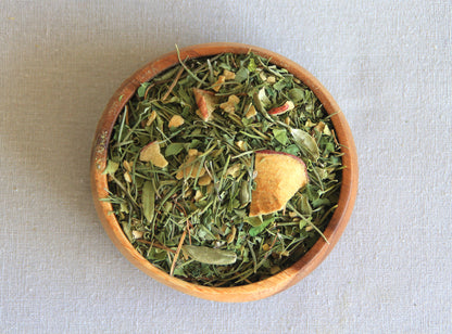 Herbal blend Mind Tonic in a wooden bowl, allows us to see all the ingredients; yerba mate, dried apple, rosemary, cardamome, moringa
