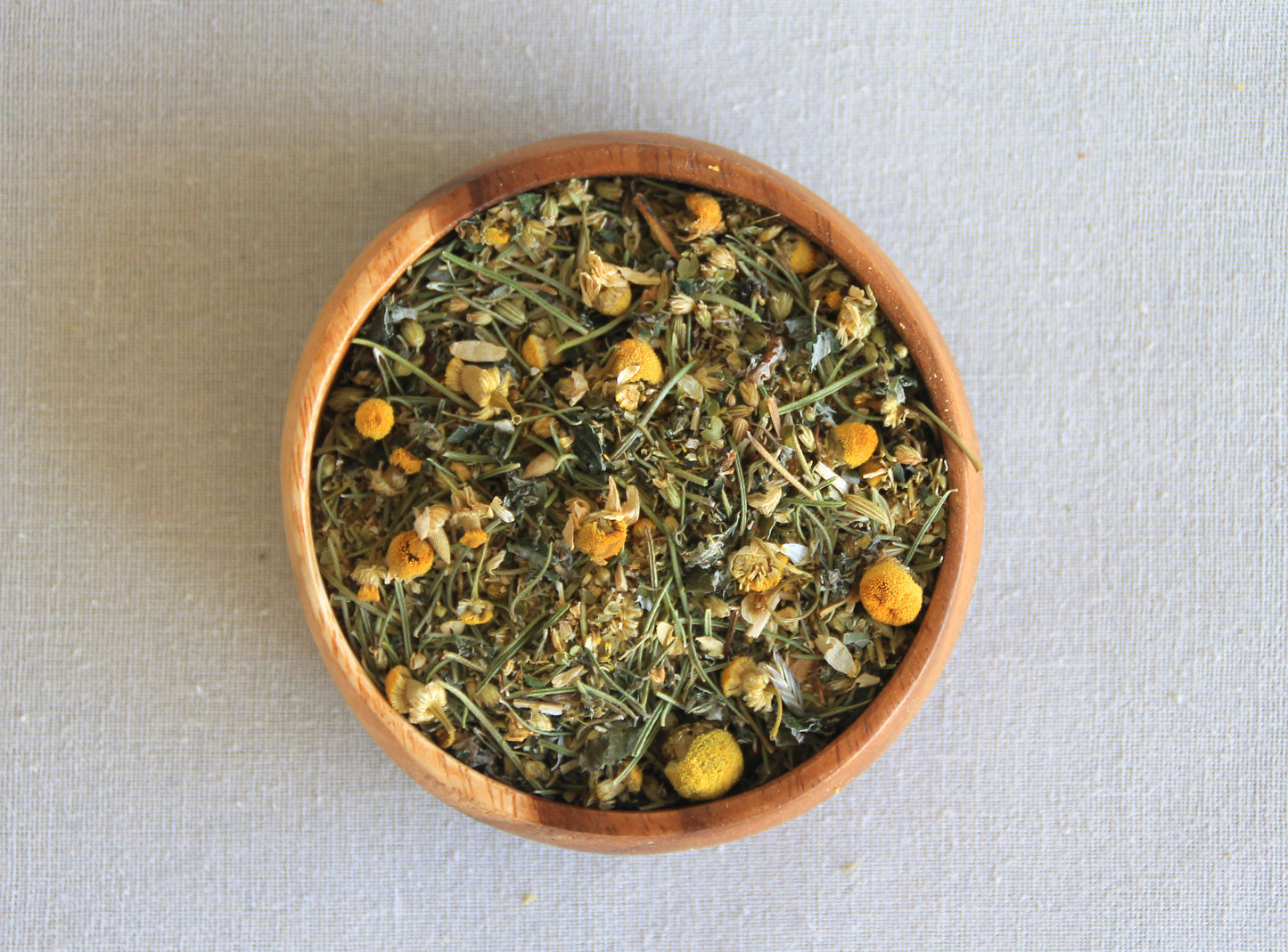 Herbal blend Moon cycle in a wooden bowl, allows us to see all the ingredients; camomile, rosemary, raspberry leaf, yarrow, oregano and fennel seeds