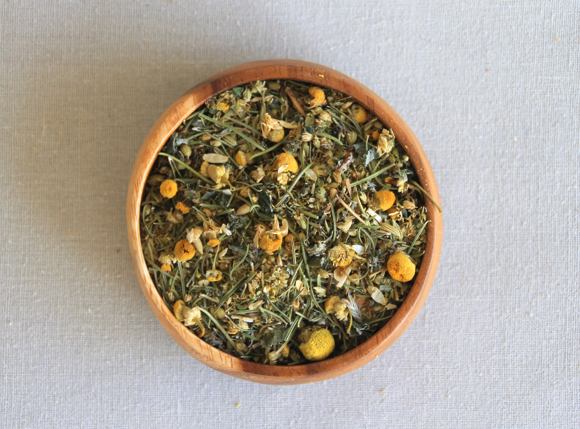 Herbal blend Moon cycle in a wooden bowl, allows us to see all the ingredients; camomile, rosemary, raspberry leaf, yarrow, oregano and fennel seeds