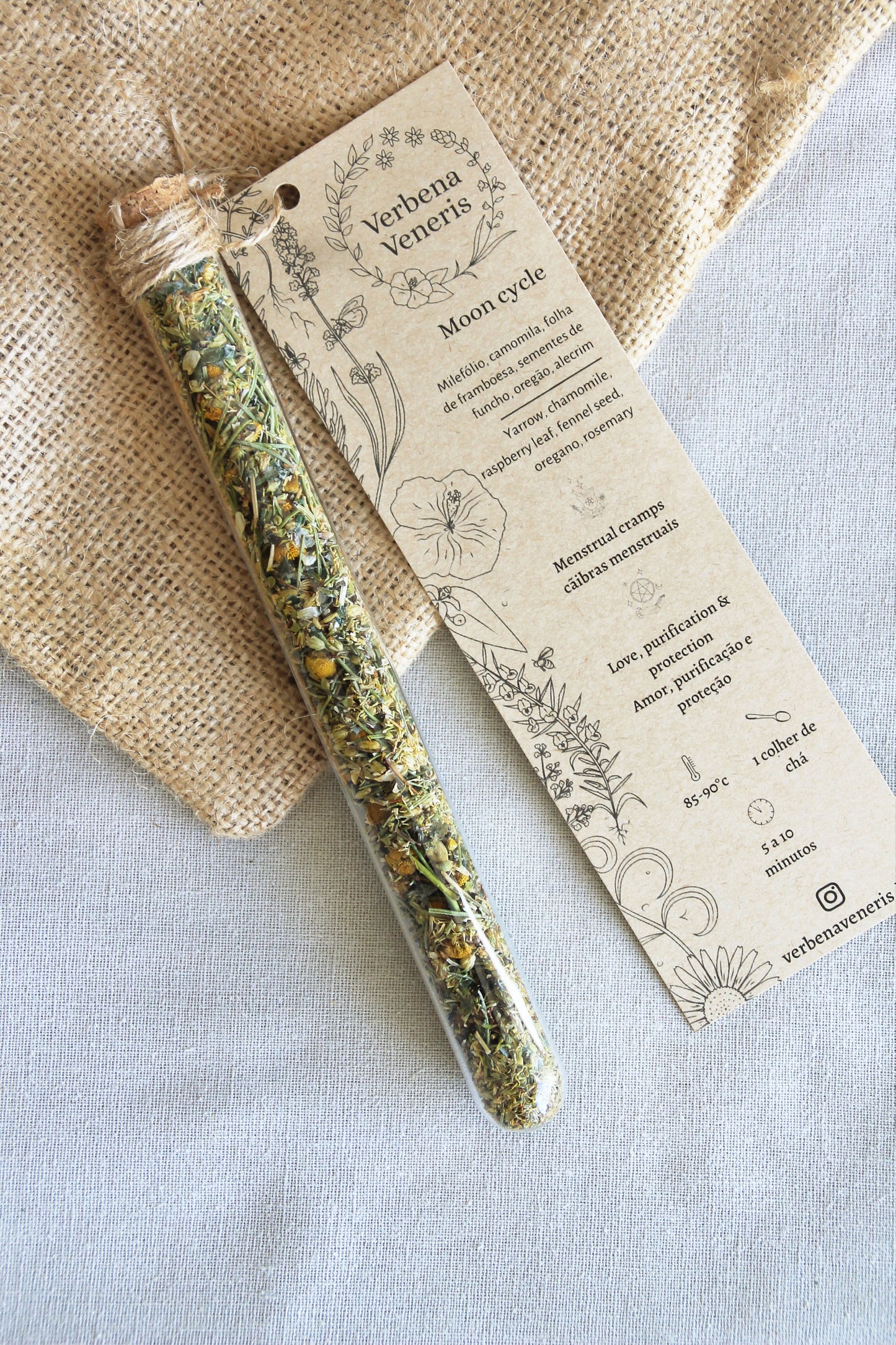 chemist glass tube closed with a cork top tighten with some  ropes. It contains the herbal blend called Moon cycle A kraft label tag is attached to it, with all the information regarding the herbs.