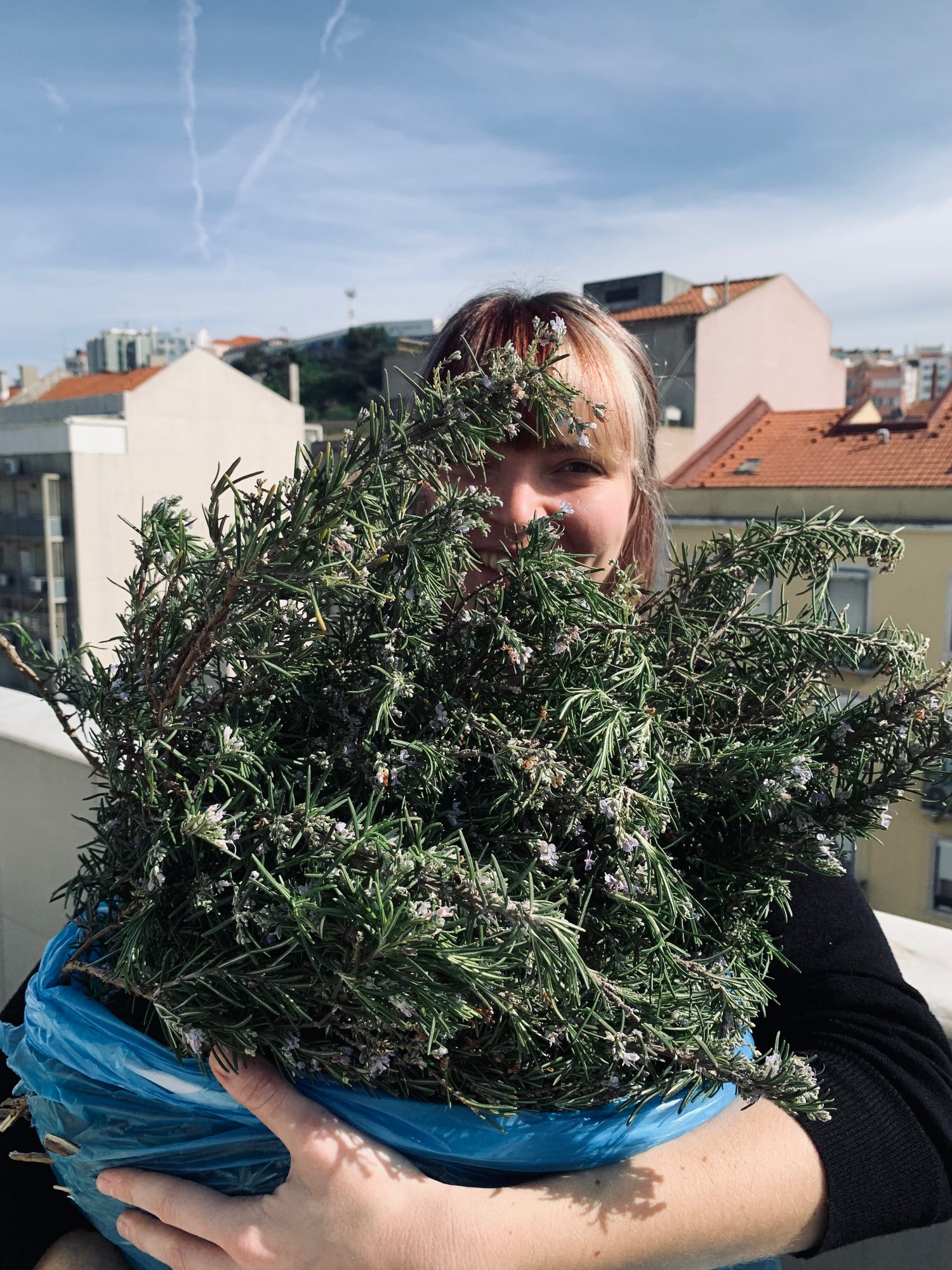 a woman holding a bunch of rosemary sprigs in her arms